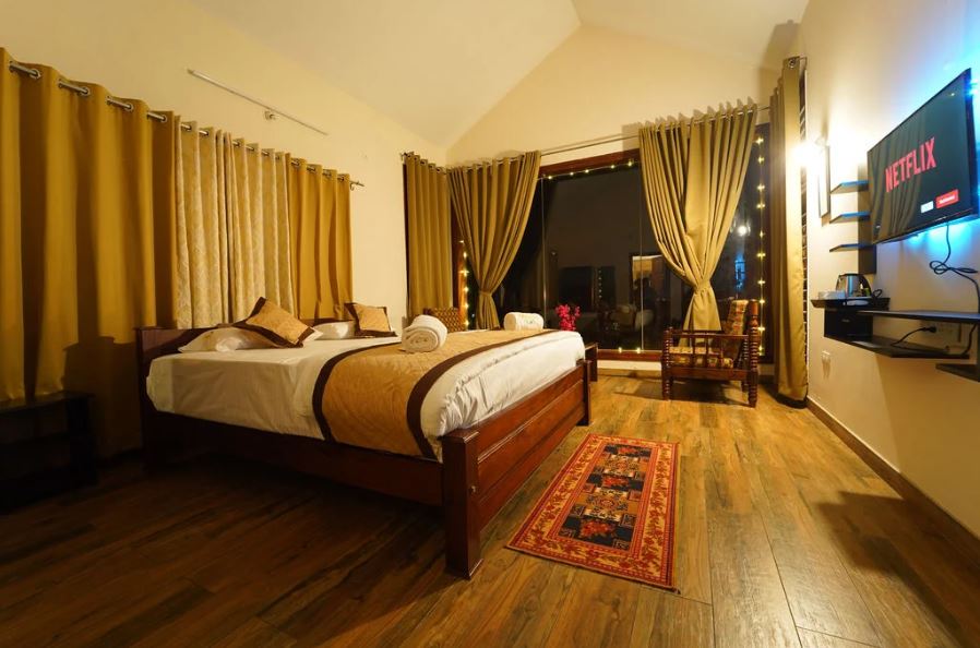 Story of the Stay:
 
This villa, nestled in the rolling hills of Chikkamagaluru, lies in an excellent spot with serene nature and notable sites within easy reach to visit. Nearby attractions include Mullayanagiri Peak, which happens to be the highest peak in Karnataka, offering panoramic views as well as a scenic trek. Baba Budangiri, with serene surroundings and spiritual significance, is not so far from there. Bhadra Wildlife Sanctuary is a place offering the close-to-nature discovery of local wildlife, especially elephants and different bird species, and is perfect for the nature lover.

 
There is much to explore by various activities that lift the experience while staying at the villa. Nature trails abound nearby, ideal for an enjoyable walk in the early morning or a challenging hike. For the more adventurous, guided treks find exciting views. Evenings are also lively and active fun with karaoke gatherings of groups and a campfire setup that gives warmth and ambiance for story-telling and music-making under the stars. This means that there will always be some exciting and memorable activity set in place for a day at the villa.

 
The villa is perfect for a couple, family, or a group where relaxation and reconnection with nature or even a memorable stay awaits. The activities at the villa, the family-friendly environment, and the scenic views create a holistic experience for guests of all types. For couples, the villa provides a romantic mountain backdrop while families and groups can spend time bonding interestingly and variegated. Additionally, the peaceful surroundings make it an excellent choice for the solitary seeking some quiet.

 
What We Love:
 
Spacious Interiors:
There are three types of rooms in the villa, catering to different tastes. The glass view premium room allows guests an all-inclusive experience through the large glass windows offering full panoramic views for those who would like to take time and enjoy the beauty around them. Premium rooms, with extra comfort and space, may serve any guest who intends to stay longer or any family with extra people. Finally, the Standard Rooms are intended to be small and cozy with all essentials for a shorter stay. Every room has been thoughtfully designed to create a welcoming and relaxing atmosphere in which comfort and the charm of the natural surroundings blend in.

 
Location:
This villa, nestled in the rolling hills of Chikkamagaluru, lies in an excellent spot with serene nature and notable sites within easy reach to visit. Nearby attractions include Mullayanagiri Peak, which happens to be the highest peak in Karnataka, offering panoramic views as well as a scenic trek. Baba Budangiri, with serene surroundings and spiritual significance, is not so far from there.

 
Unique Experiences:
 
Campfire:
Spend a cool evening around a campfire telling stories and singing songs, under skies that are crystal clear for stargazing.

 
Hiking:
There are many trails available in the surrounding regions, ranging from easy to more challenging routes.

 
Trekking:
Guided treks can be undertaken to higher altitude areas like peaks and viewpoints, whereby panoramic views of the surrounding landscape will await the visitors.

 
Karaoke:
Enjoy an interactive experience of a fun group activity, where you can also sing along with your favorite tunes.

 
Nearby Tourist Spots:
Mullayanagiri Peak, Baba Budangiri, Kemmanagundi and Bhadra Wildlife Sanctuary.

 
Key Amenities:
Glass View Premium Room
Premium Rooms
Standard Room
Private Events
Celebration Decoration
Luxury Bedroom
Kitchen
Mini Theater
Kettle
Work from Home
Karaoke
Hair Dryer
Smart TV
Indoor and Outdoor Games
Kitchen Items
Dining Area
Full Speed Wi-Fi
Fridge
Bath Kit
Full Solar Power
Open Theater
Fire Camp
Parking
Power Backup
Housekeeping
Room Service
Washrooms
 
Activities:
Campfire
Hiking
Trekking
Nature Trails
Karaoke
Indoor and Outdoor Games
Open Theater
Private Events
Celebration Decoration
Nearby Tourist Spots:
Mullayanagiri Peak, Baba Budangiri, Kemmanagundi and Bhadra Wildlife Sanctuary.