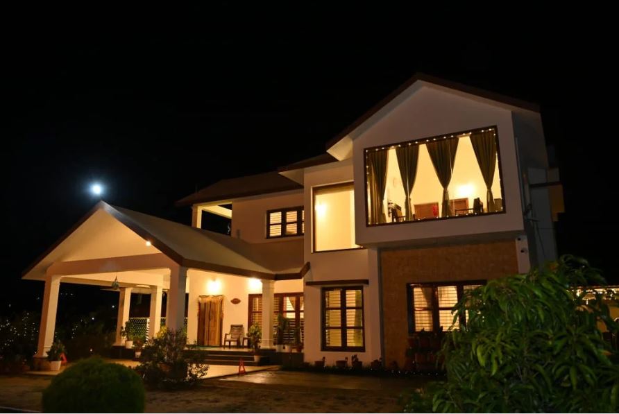 Story of the Stay:
 
This villa, nestled in the rolling hills of Chikkamagaluru, lies in an excellent spot with serene nature and notable sites within easy reach to visit. Nearby attractions include Mullayanagiri Peak, which happens to be the highest peak in Karnataka, offering panoramic views as well as a scenic trek. Baba Budangiri, with serene surroundings and spiritual significance, is not so far from there. Bhadra Wildlife Sanctuary is a place offering the close-to-nature discovery of local wildlife, especially elephants and different bird species, and is perfect for the nature lover.

 
There is much to explore by various activities that lift the experience while staying at the villa. Nature trails abound nearby, ideal for an enjoyable walk in the early morning or a challenging hike. For the more adventurous, guided treks find exciting views. Evenings are also lively and active fun with karaoke gatherings of groups and a campfire setup that gives warmth and ambiance for story-telling and music-making under the stars. This means that there will always be some exciting and memorable activity set in place for a day at the villa.

 
The villa is perfect for a couple, family, or a group where relaxation and reconnection with nature or even a memorable stay awaits. The activities at the villa, the family-friendly environment, and the scenic views create a holistic experience for guests of all types. For couples, the villa provides a romantic mountain backdrop while families and groups can spend time bonding interestingly and variegated. Additionally, the peaceful surroundings make it an excellent choice for the solitary seeking some quiet.

 
What We Love:
 
Spacious Interiors:
There are three types of rooms in the villa, catering to different tastes. The glass view premium room allows guests an all-inclusive experience through the large glass windows offering full panoramic views for those who would like to take time and enjoy the beauty around them. Premium rooms, with extra comfort and space, may serve any guest who intends to stay longer or any family with extra people. Finally, the Standard Rooms are intended to be small and cozy with all essentials for a shorter stay. Every room has been thoughtfully designed to create a welcoming and relaxing atmosphere in which comfort and the charm of the natural surroundings blend in.

 
Location:
This villa, nestled in the rolling hills of Chikkamagaluru, lies in an excellent spot with serene nature and notable sites within easy reach to visit. Nearby attractions include Mullayanagiri Peak, which happens to be the highest peak in Karnataka, offering panoramic views as well as a scenic trek. Baba Budangiri, with serene surroundings and spiritual significance, is not so far from there.

 
Unique Experiences:
 
Campfire:
Spend a cool evening around a campfire telling stories and singing songs, under skies that are crystal clear for stargazing.

 
Hiking:
There are many trails available in the surrounding regions, ranging from easy to more challenging routes.

 
Trekking:
Guided treks can be undertaken to higher altitude areas like peaks and viewpoints, whereby panoramic views of the surrounding landscape will await the visitors.

 
Karaoke:
Enjoy an interactive experience of a fun group activity, where you can also sing along with your favorite tunes.

 
Nearby Tourist Spots:
Mullayanagiri Peak, Baba Budangiri, Kemmanagundi and Bhadra Wildlife Sanctuary.

 
Key Amenities:
Glass View Premium Room
Premium Rooms
Standard Room
Private Events
Celebration Decoration
Luxury Bedroom
Kitchen
Mini Theater
Kettle
Work from Home
Karaoke
Hair Dryer
Smart TV
Indoor and Outdoor Games
Kitchen Items
Dining Area
Full Speed Wi-Fi
Fridge
Bath Kit
Full Solar Power
Open Theater
Fire Camp
Parking
Power Backup
Housekeeping
Room Service
Washrooms
 
Activities:
Campfire
Hiking
Trekking
Nature Trails
Karaoke
Indoor and Outdoor Games
Open Theater
Private Events
Celebration Decoration
Nearby Tourist Spots:
Mullayanagiri Peak, Baba Budangiri, Kemmanagundi and Bhadra Wildlife Sanctuary.